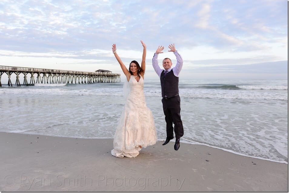 Bride and groom jumping in front of the ocean