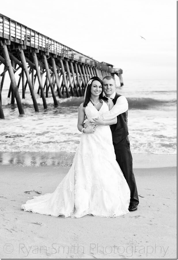 Black and white portrait of bride and groom in front of Myrtle Beach State Park pier