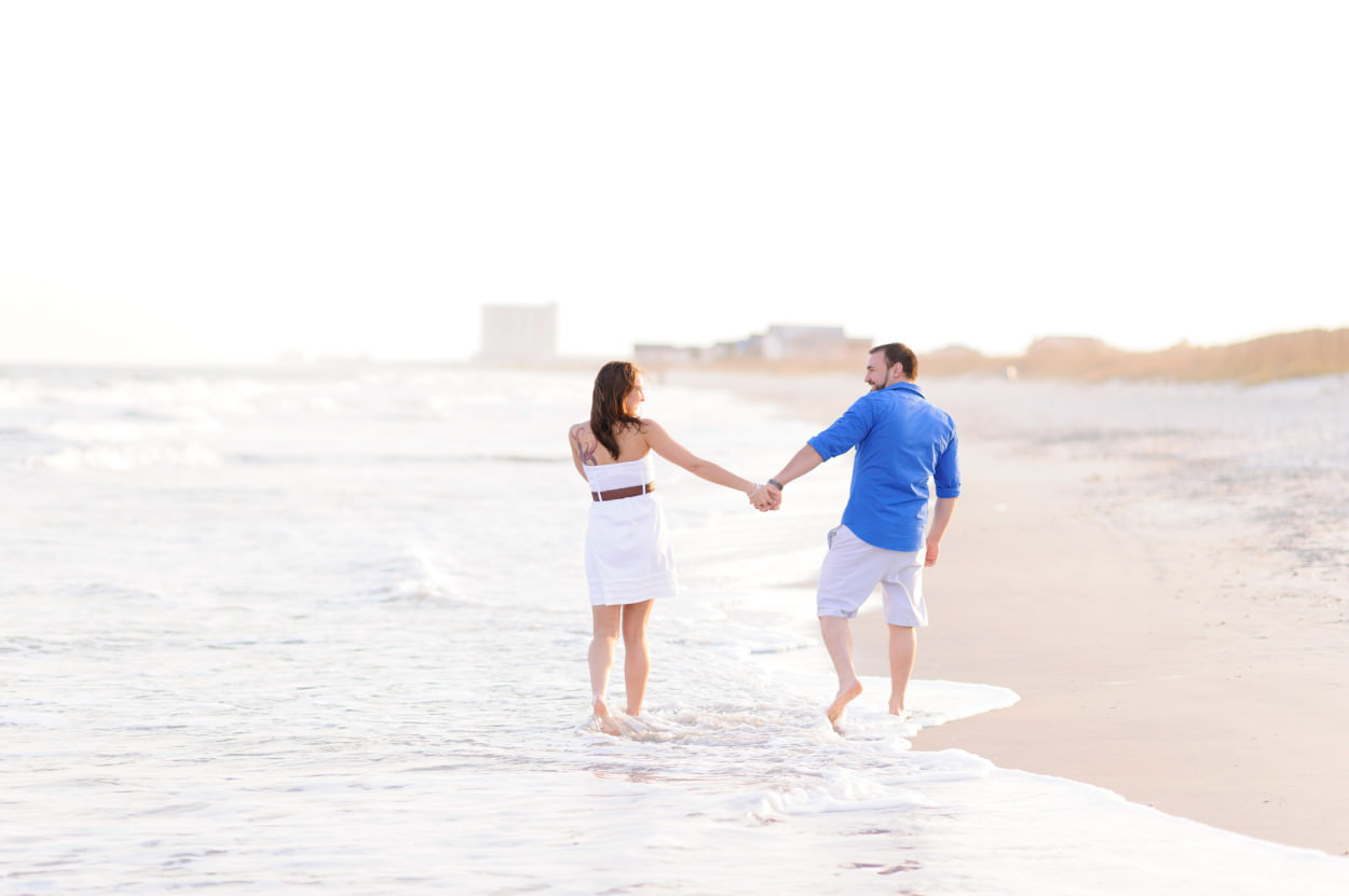 Couple holding hands and walking down the beach together