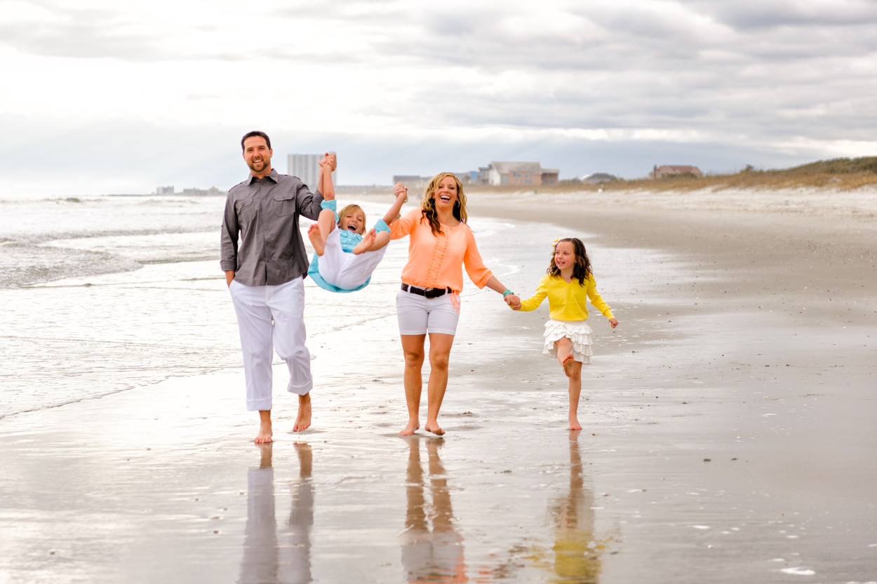 Mom and dad swinging son in the air at the beach