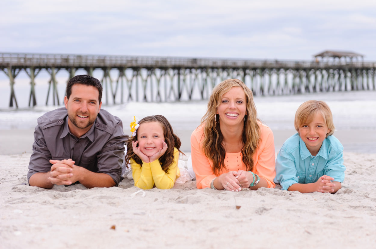 Cute family of 4 laying in the sand