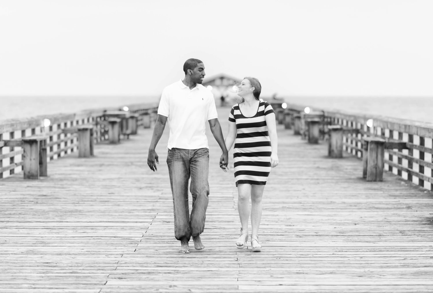 Couple holding hands walking down the state park pier