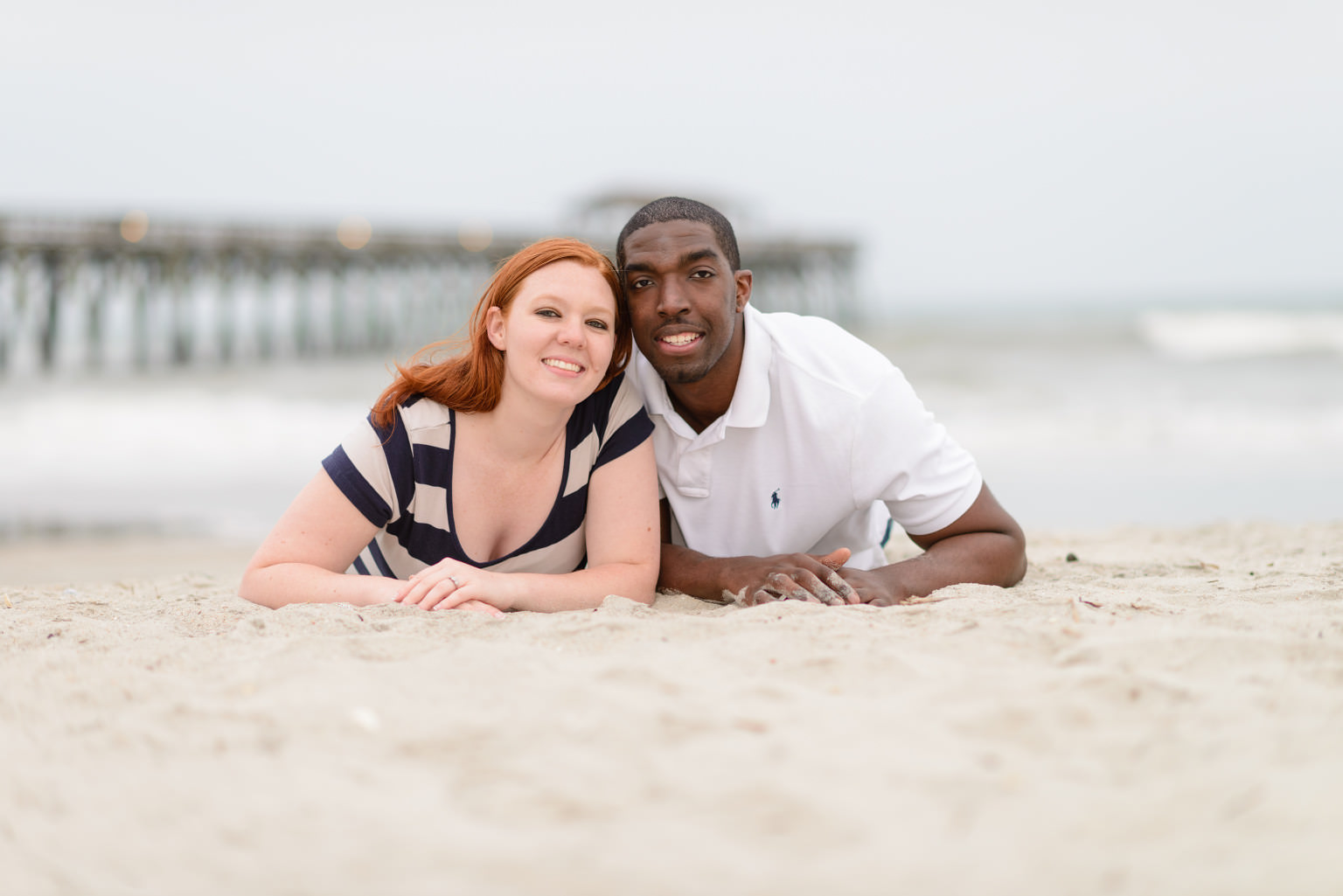 Engagement portrait laying in sand looking up at Myrtle Beach State Park
