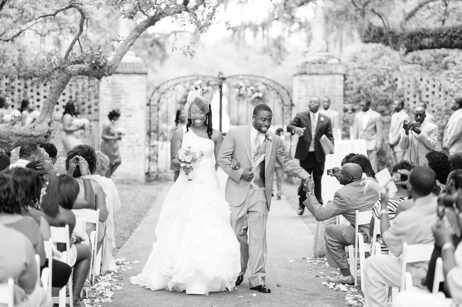 Black and white of couple walking down the isle and looking happy