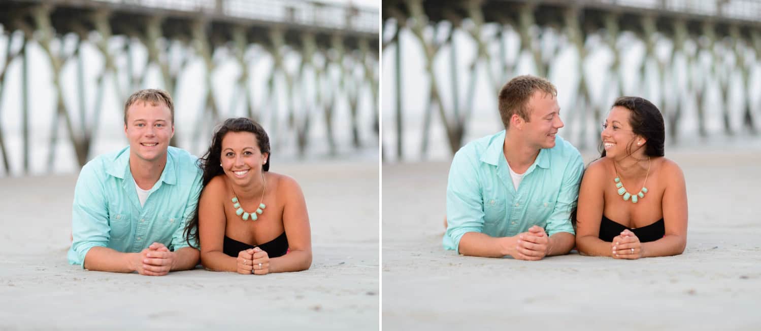 Couple laying in the sand together in front of the pier