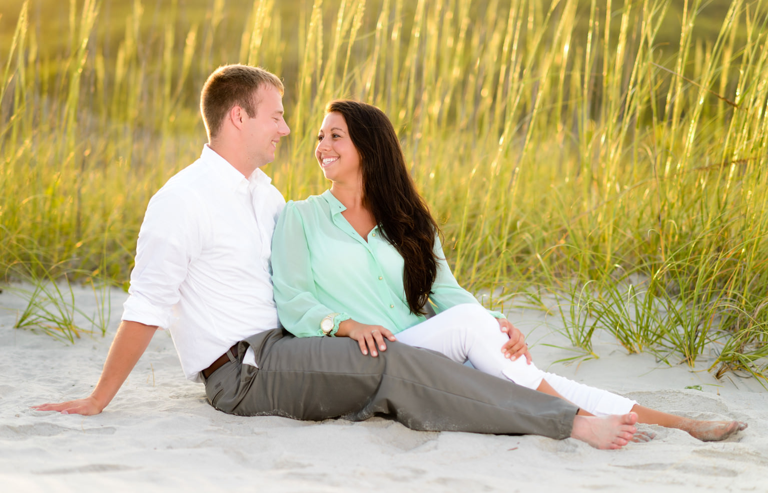 Couple smiling at each other with sunset hitting the sea oats in the background - Myrtle Beach