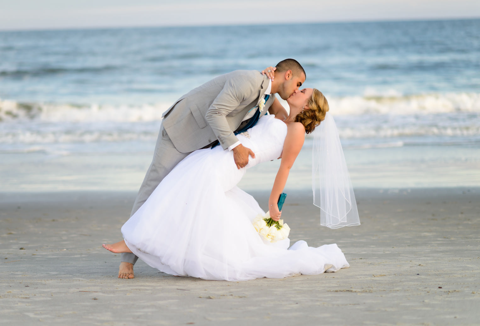 Dipping bride back for a kiss in front of the ocean