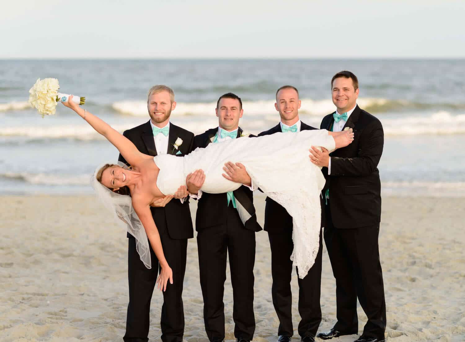 Groomsmen lifting up the bride at the Ocean Club