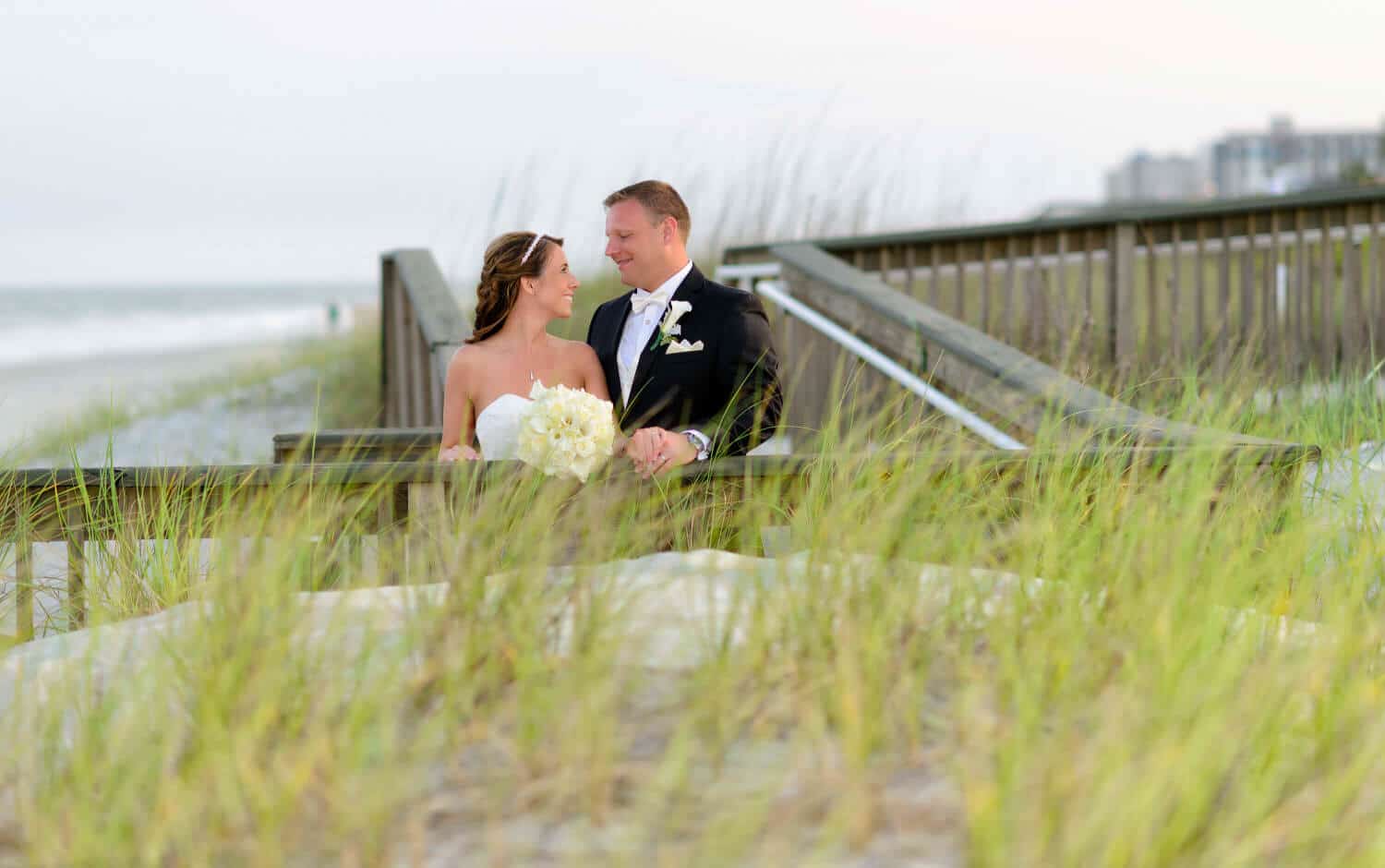 Portrait of couple on walkway with sea oats in foreground