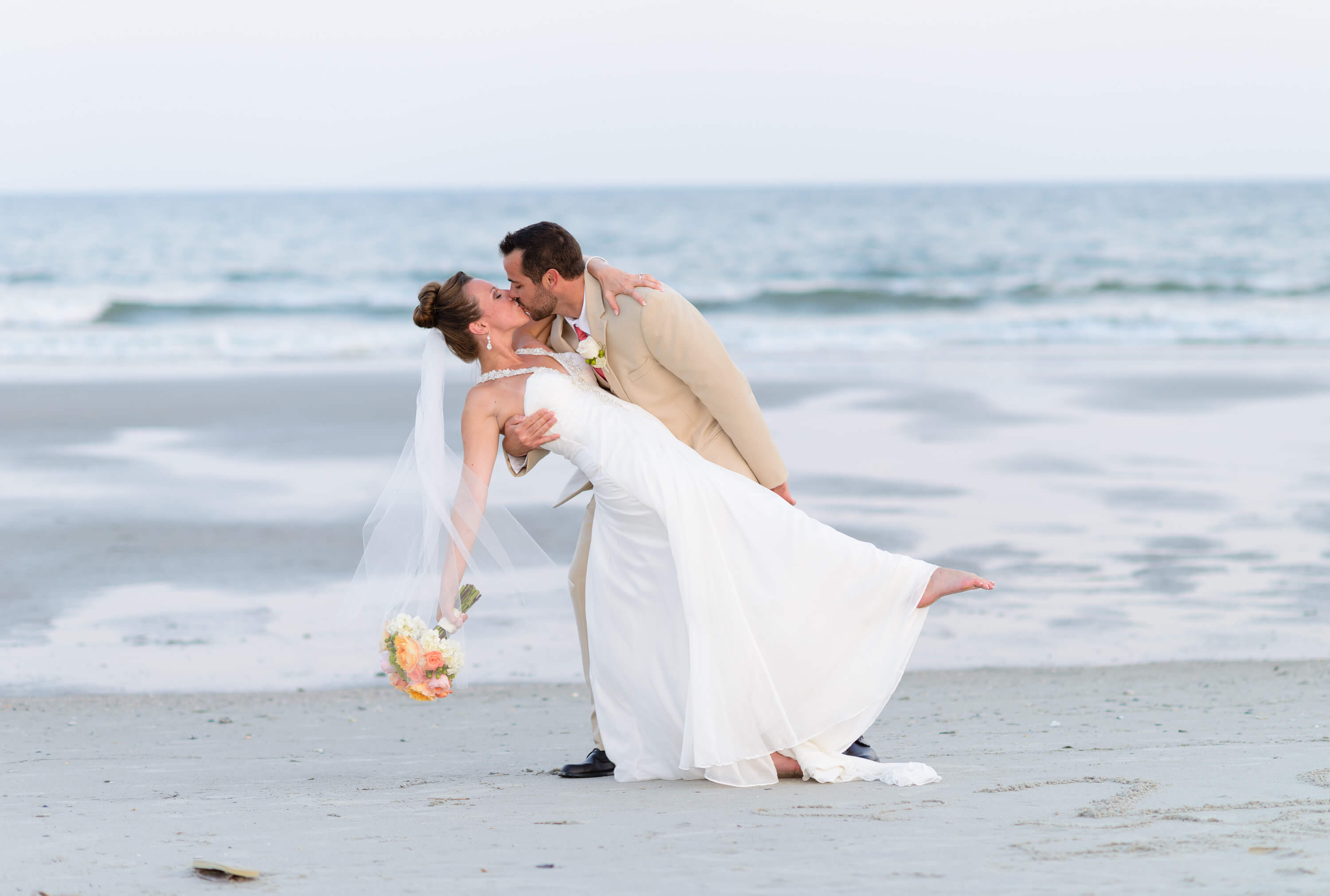 Dipping bride back for a kiss in front of the ocean