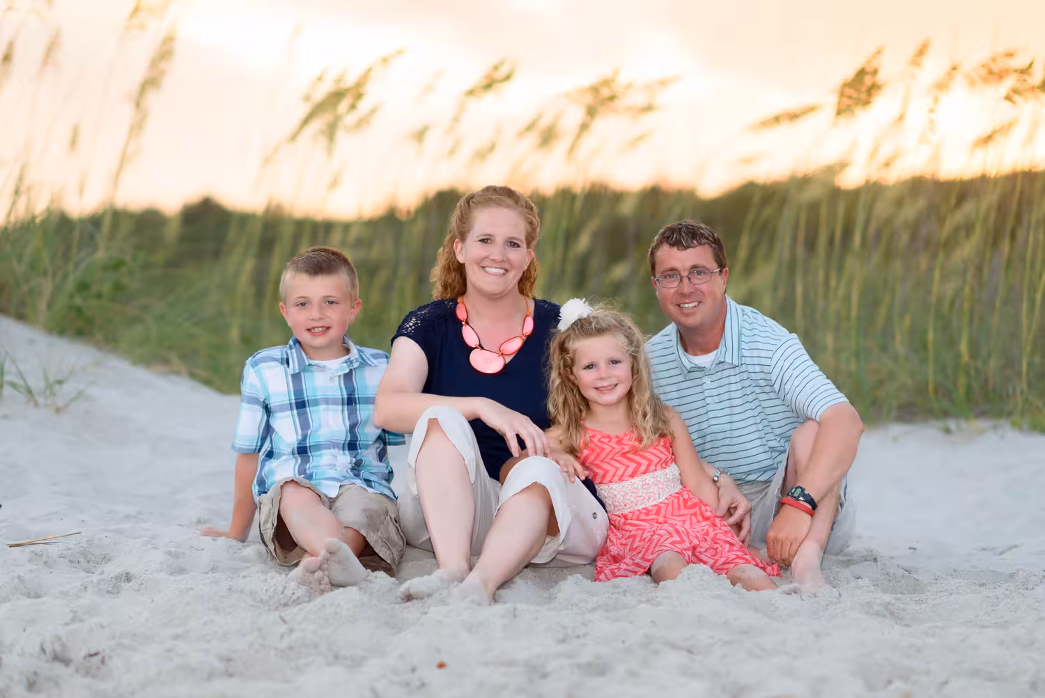 Family of 4 in front of a beautiful sunset by the sea oats