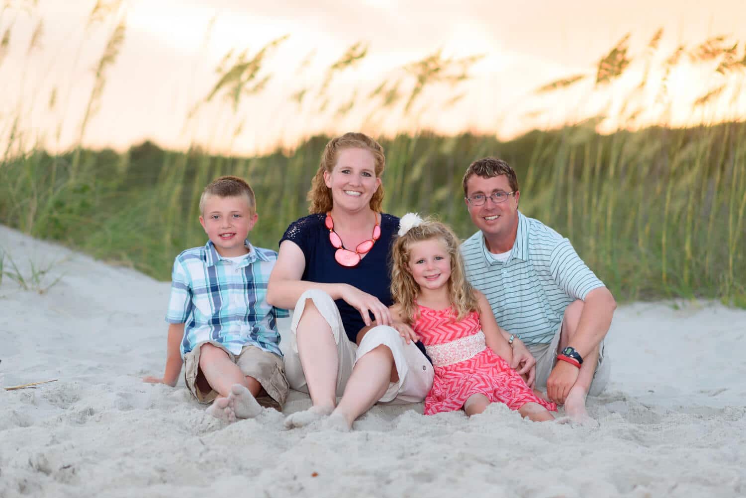 Family of 4 in front of a beautiful sunset by the sea oats