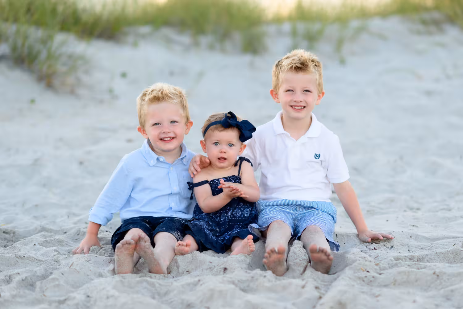 Two brothers with baby sister sitting by the sand dunes - Myrtle