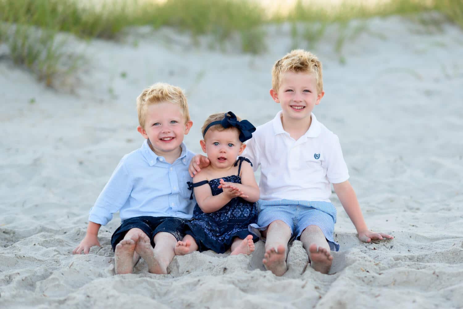 Two brothers with baby sister sitting by the sand dunes - Myrtle