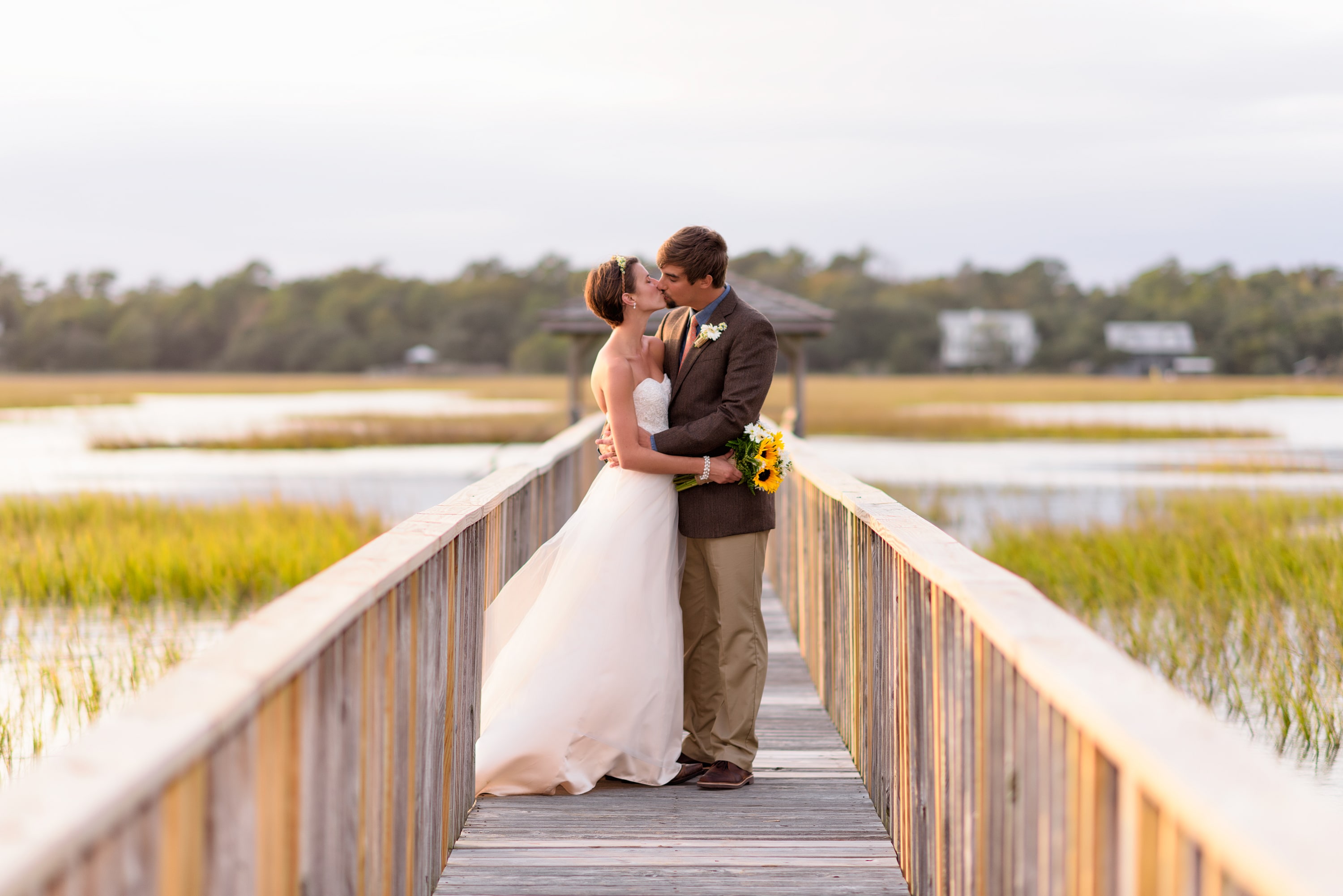 Bride and groom kissing on a marsh walkway in Pawleys Island