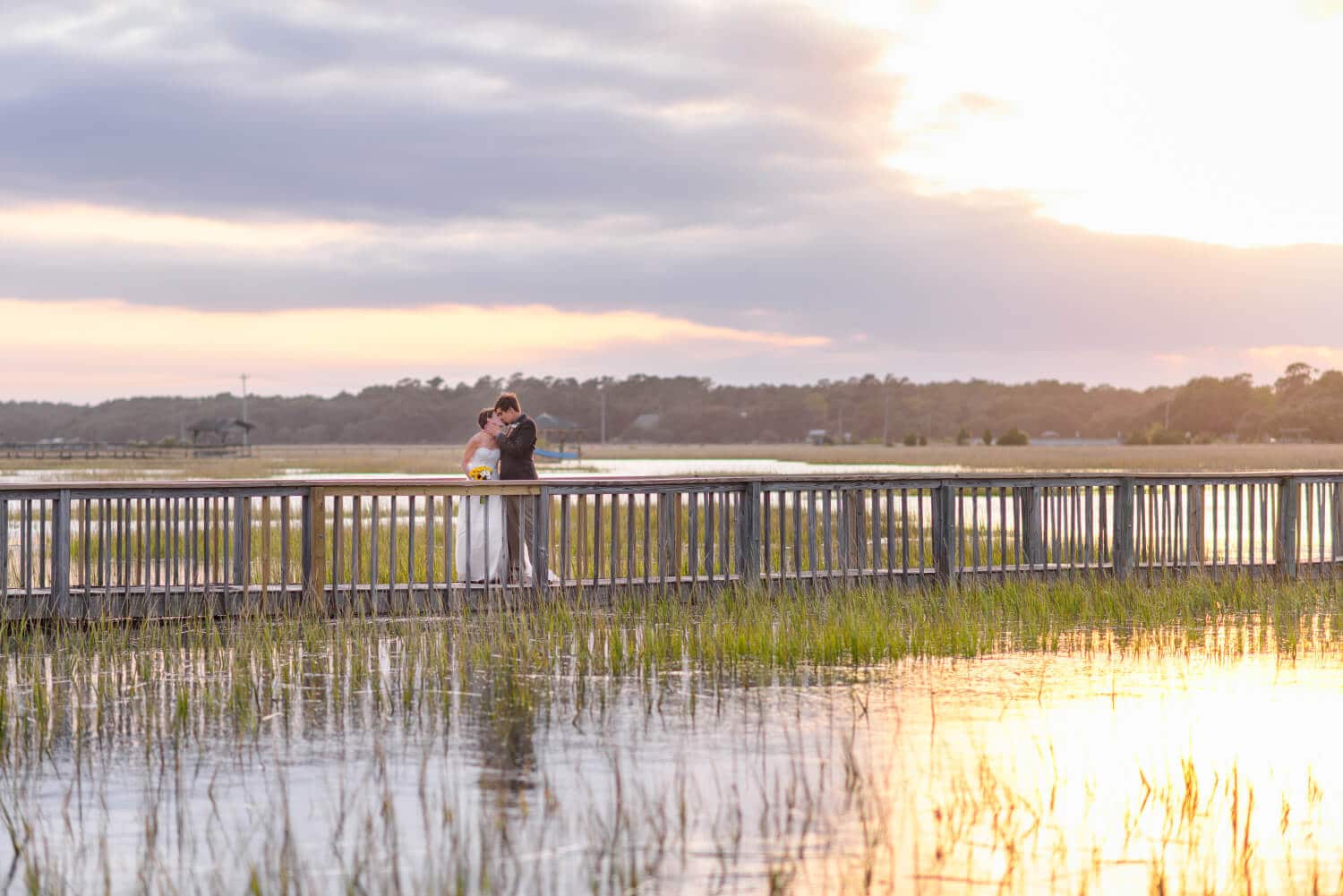 Beautiful sunset refecting in marsh with couple kissing on walkway