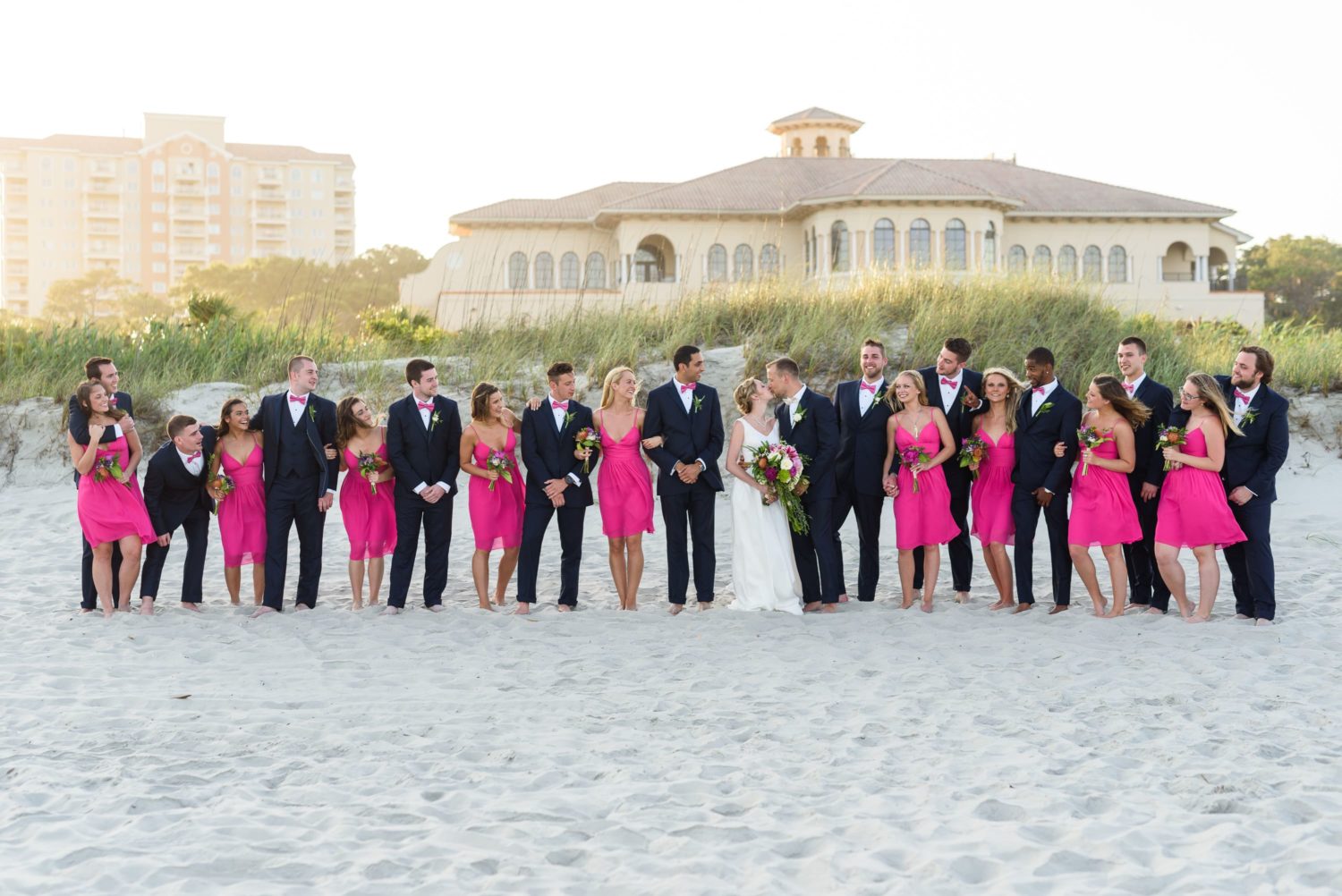Bride and groom kissing with bridal party -  Grande Dunes Ocean Club