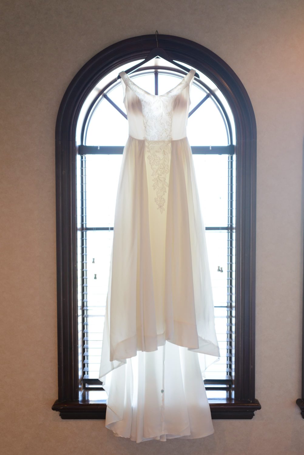 Bride's classic dress hanging in a window -  Grande Dunes Ocean Club