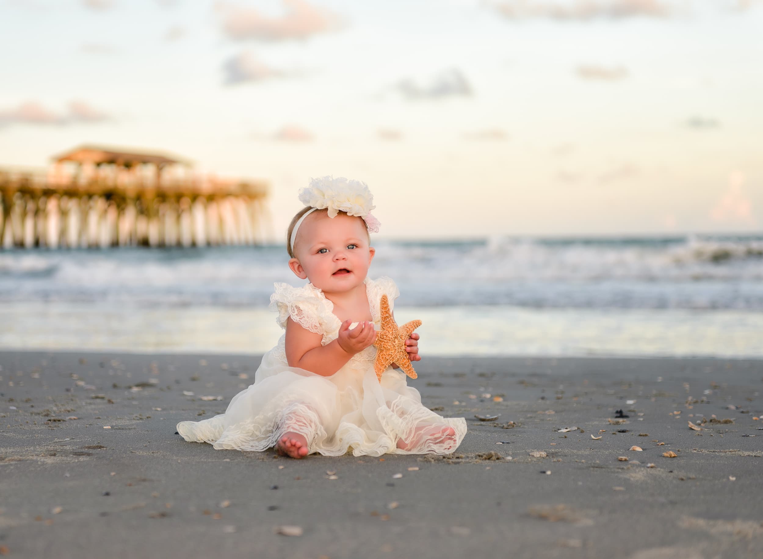 Baby holding a starfish in front of the ocean - Myrtle Beach State Park
