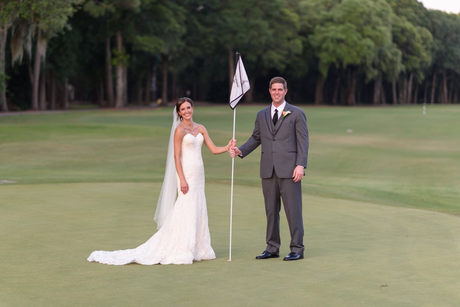 Bride and groom holding golf course flag - Pawleys Plantation