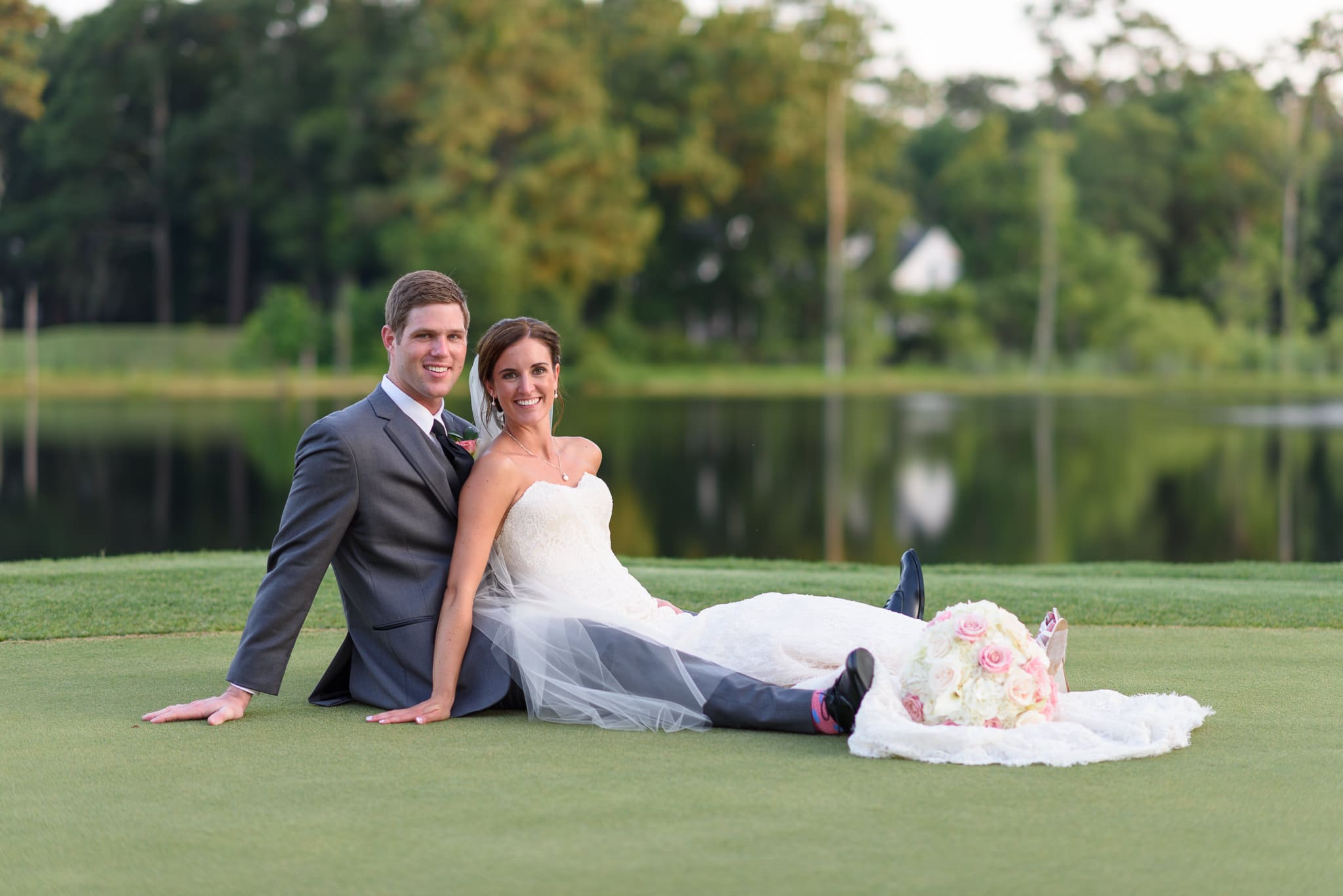 Bride laying with groom on greens - Pawleys Plantation