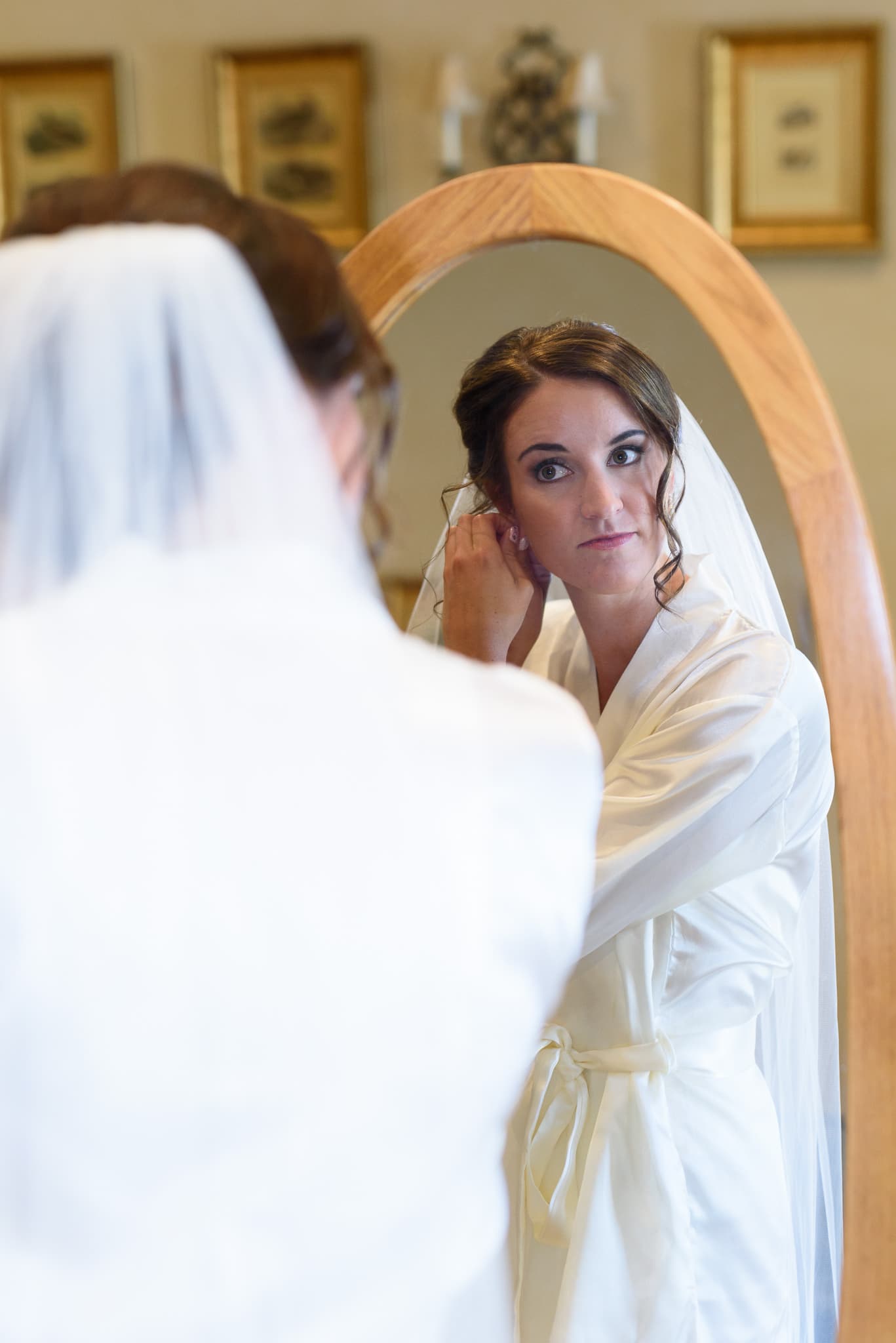 Bride putting on earrings in mirror - Pawleys Plantation