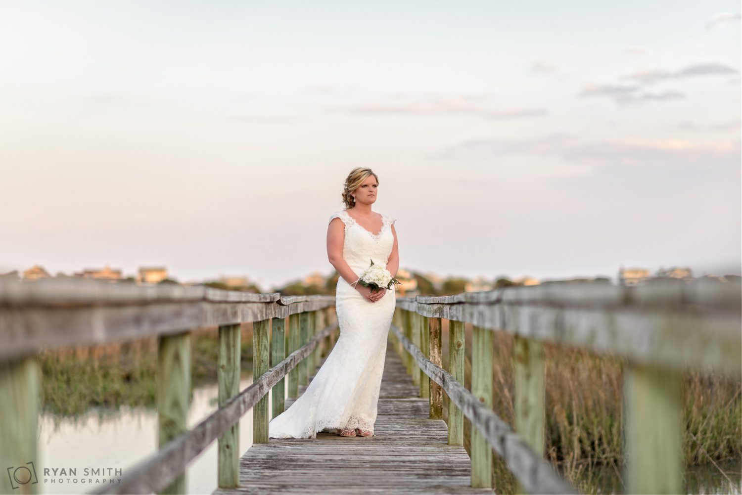 Bride standing on a marsh walkway looking at the sunset Pawleys Island