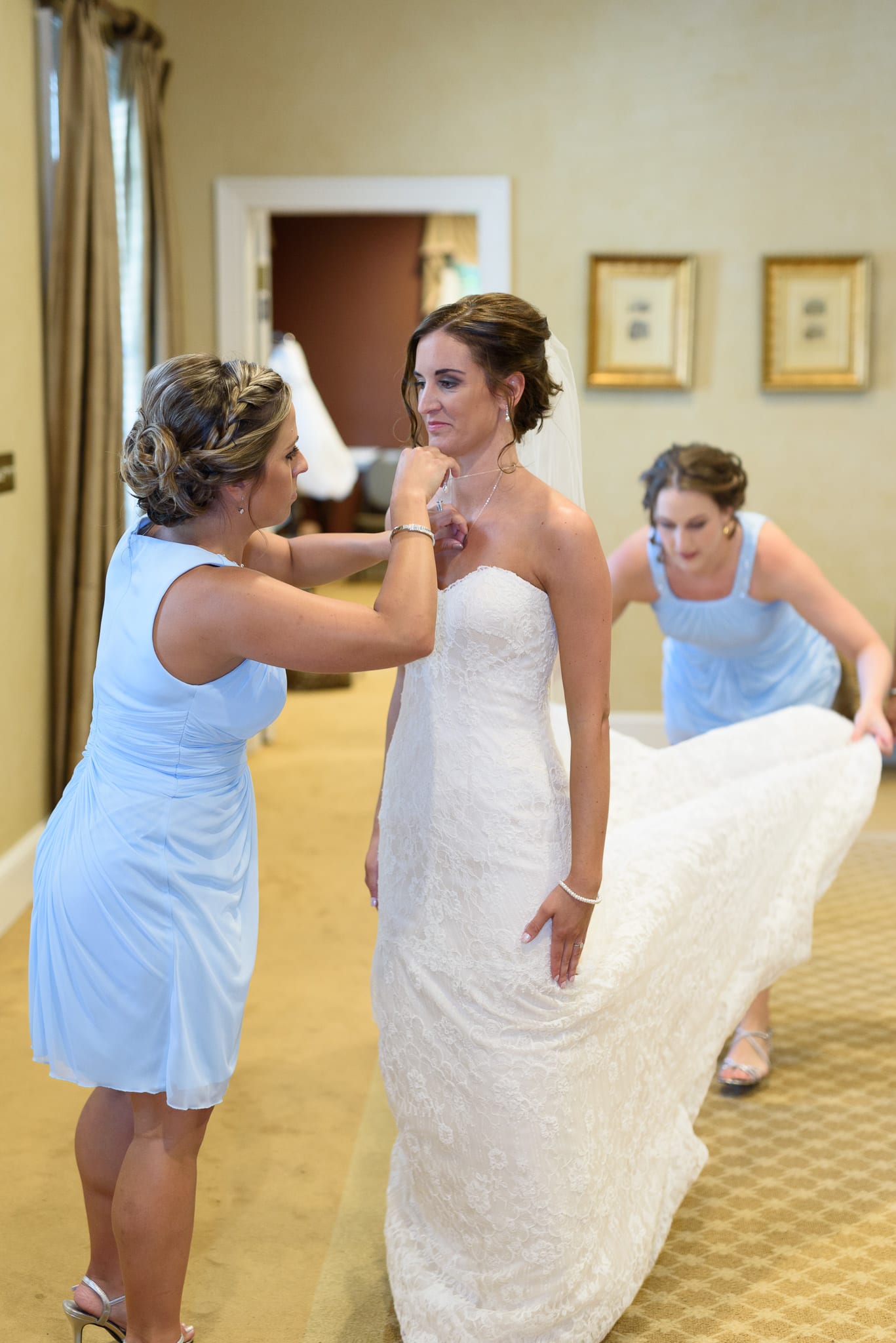 Bridesmaids helping bride put on dress - Pawleys Plantation
