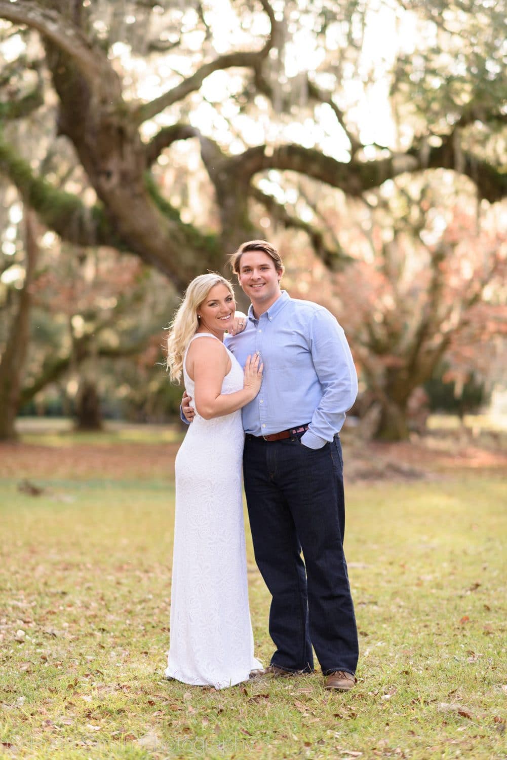 Couple smiling with sunlight coming through oak trees - Litchfield Plantation