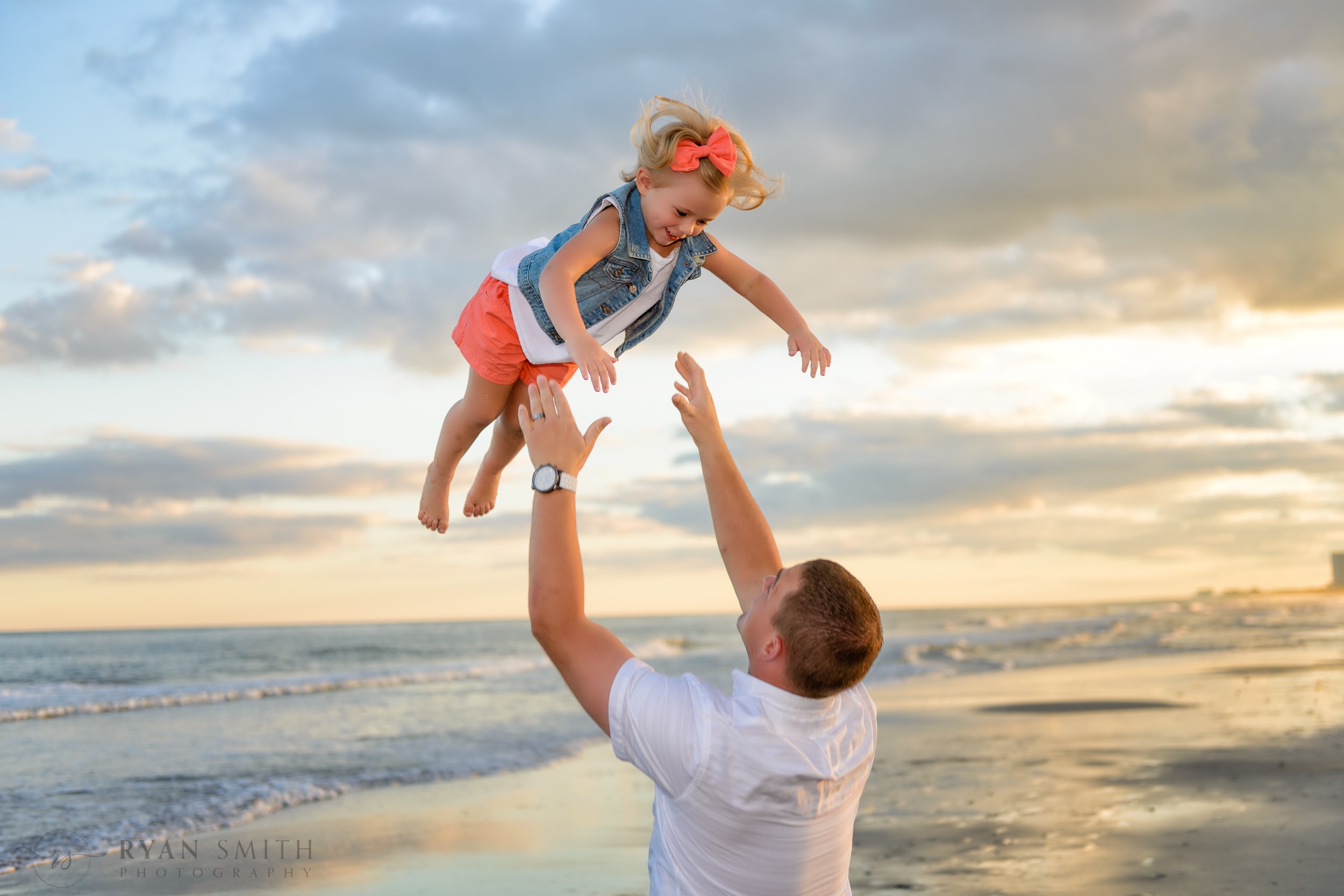 Dad throwing daughter into the air with beautiful sunset - Myrtle Beach State Park
