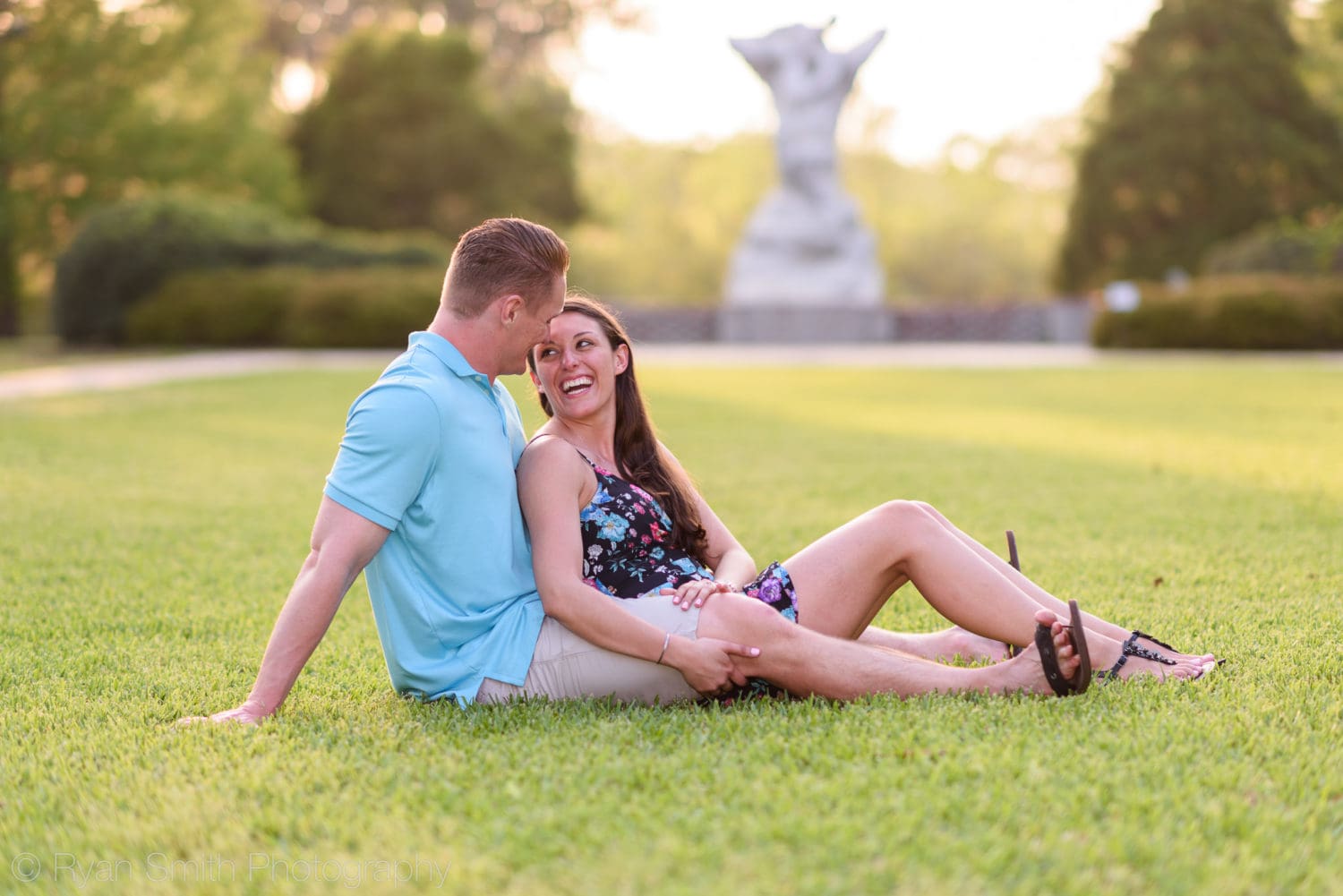 Girl smiling at fiancé in the grass - Brookgreen Gardens