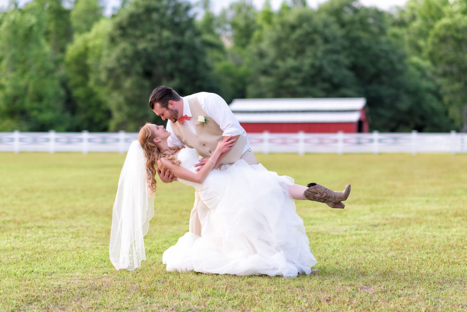 Groom dipping back bride in front of barn - Wildberry Farm