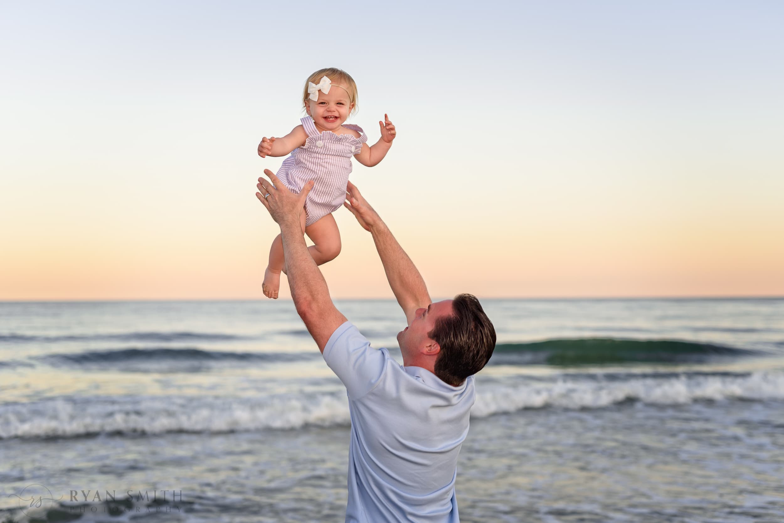 Happy baby girl getting tossed into the air - Myrtle Beach State Park