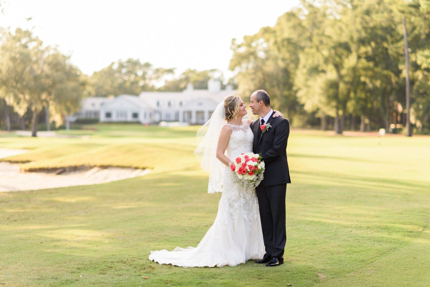Bride and groom with clubhouse in the background - Pawleys Plantation