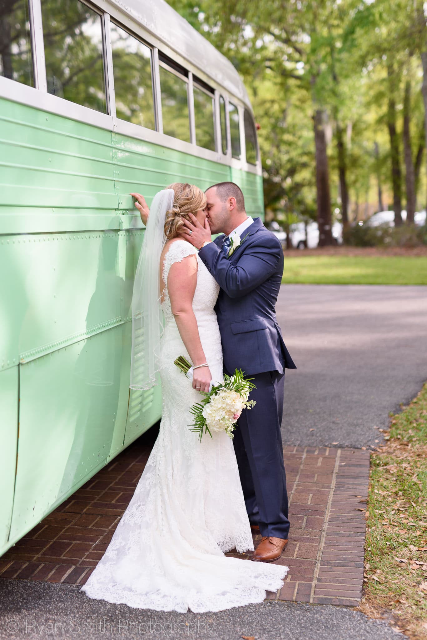 Bride and groom kissing beside the classic green bus - Pawleys Plantation