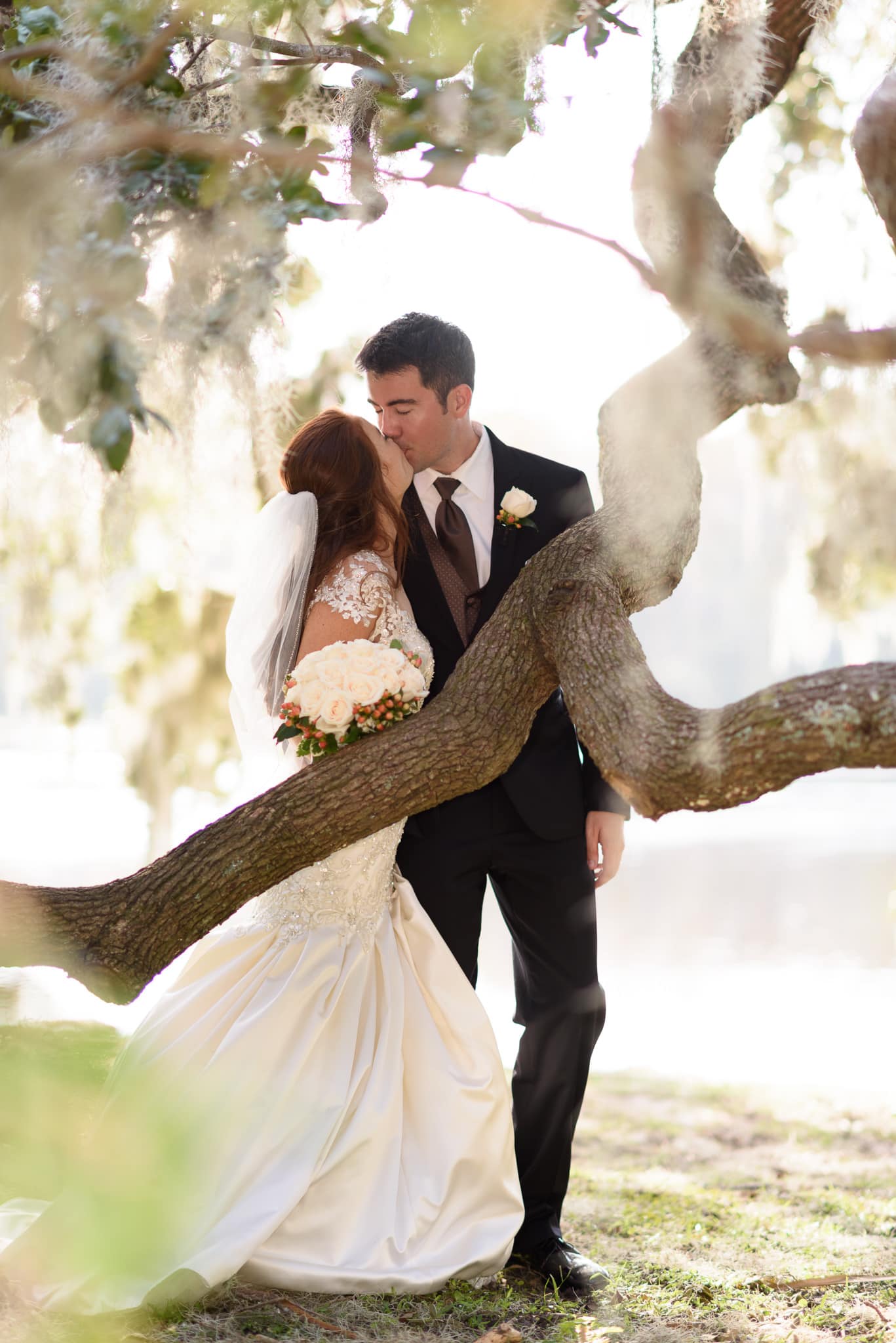 Bride and groom kissing under an oak tree - Wachesaw Plantation