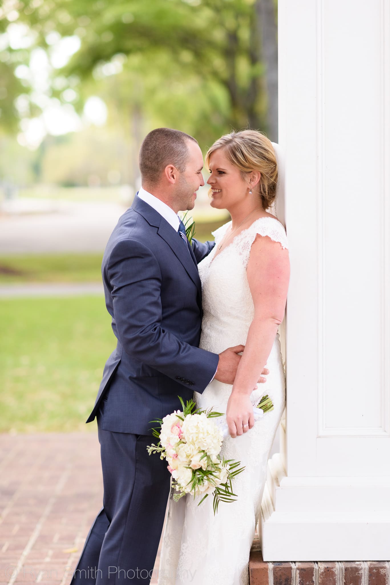 Bride and groom leaning against the entryway columns - Pawleys Plantation