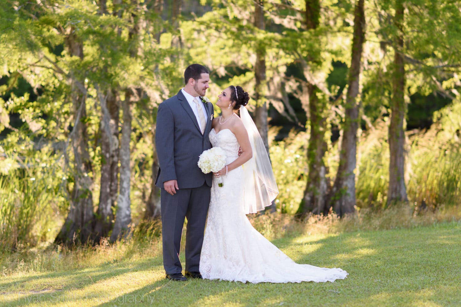 Bride and groom smiling at each other by the lake - Upper Mill Plantation