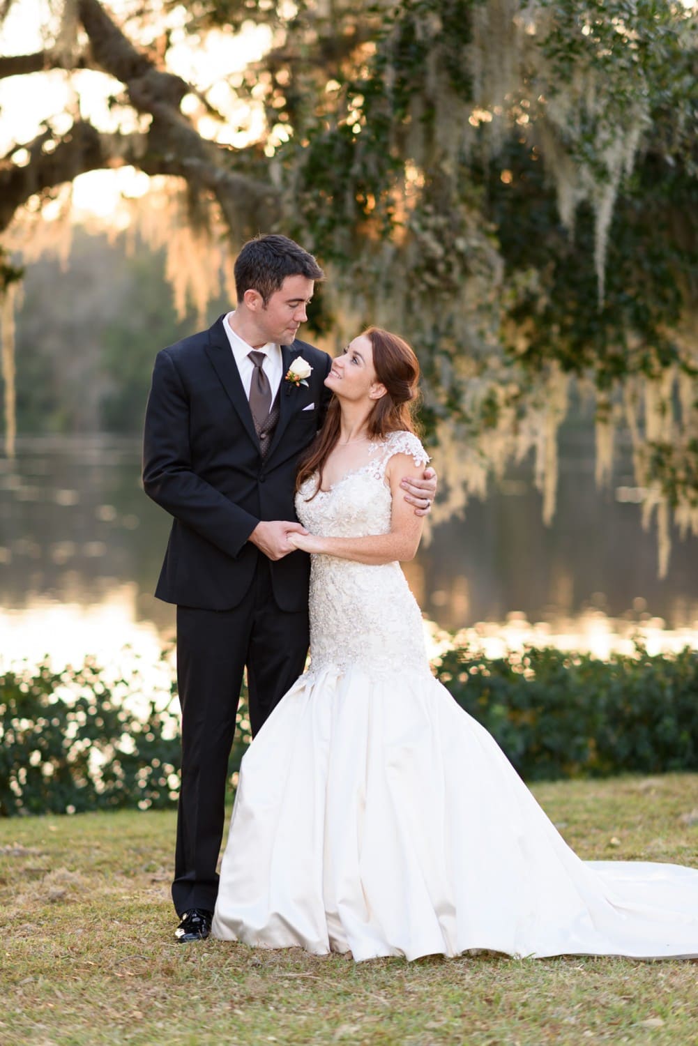 Bride and groom smiling at each other by the Waccamaw River at sunset - Wachesaw Plantation