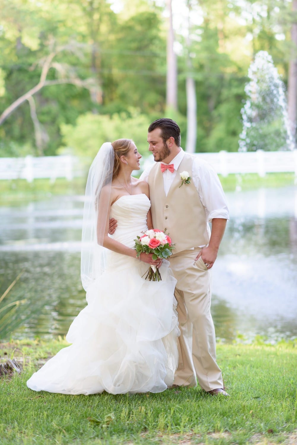 Bride and groom smiling at each other in front of lake - Wildberry Farm