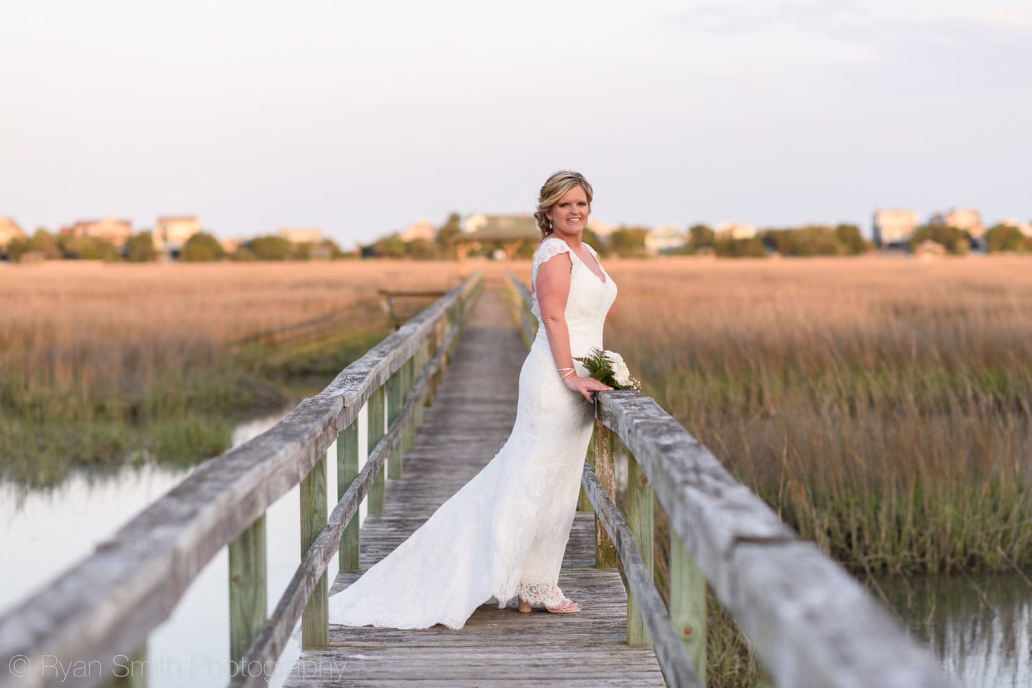 Bride leaning against a railing on a marsh boardwalk  - Pawleys Island