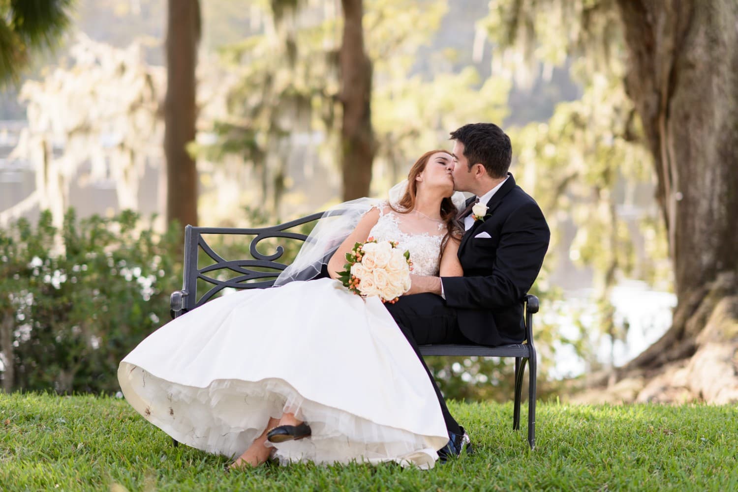 Bride leaning back against groom on a garden bench - Wachesaw Plantation