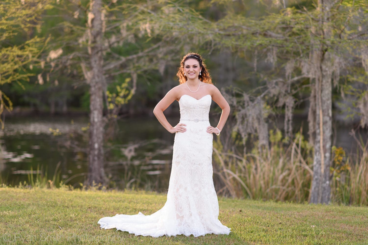 Bride posing with hands on hips in front of a lake - Upper Mill Plantation