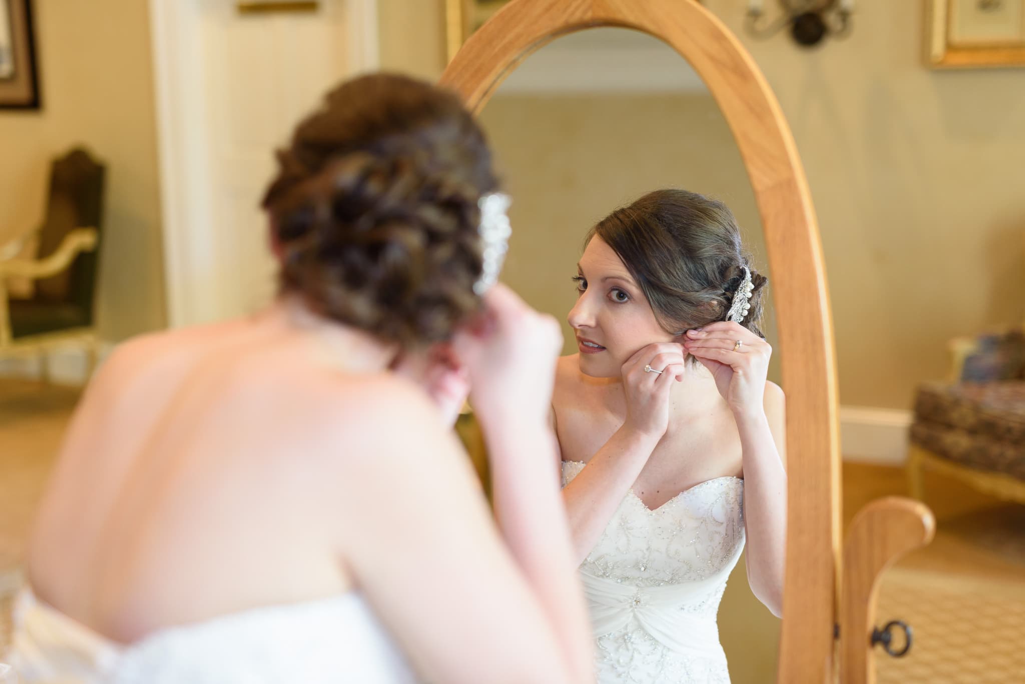 Bride putting on earing in mirror - Pawleys Plantation