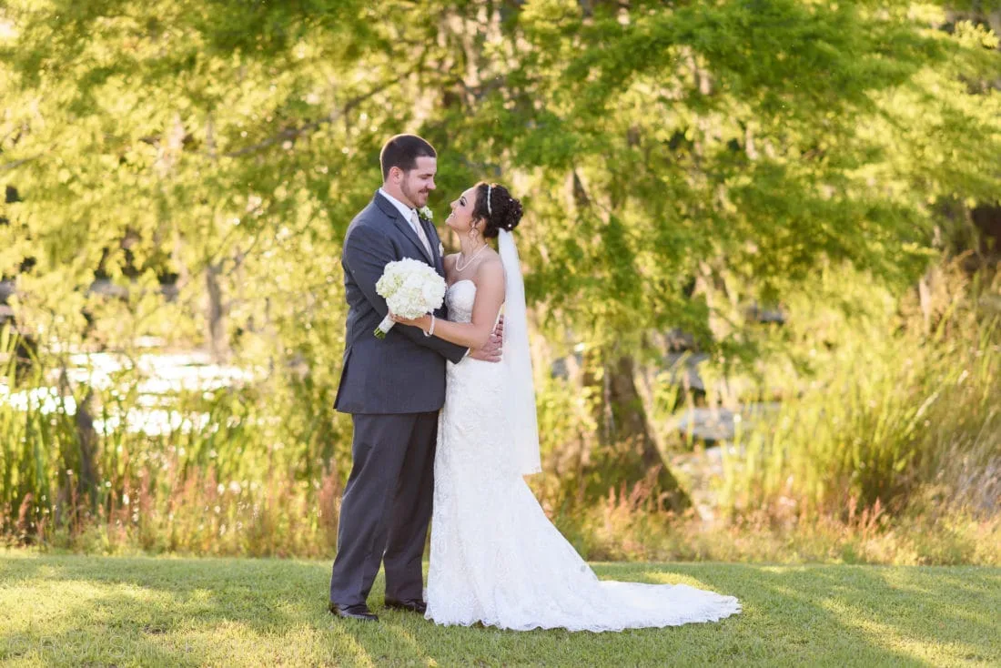 Bride smiling up at groom backlit by sunset on the lake - Upper Mill Plantation