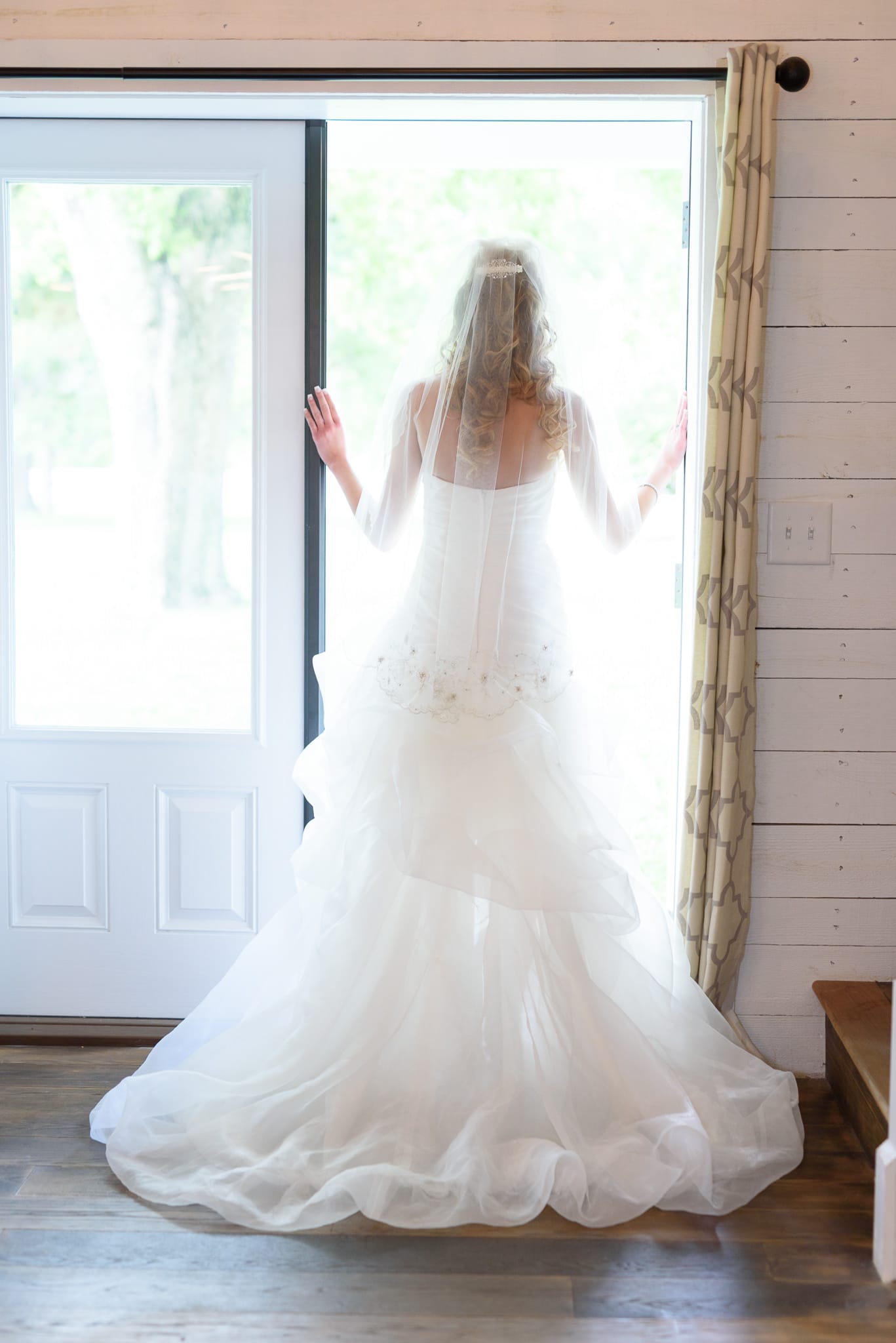 Bride standing in light from doorway and looking out - Wildberry Farm