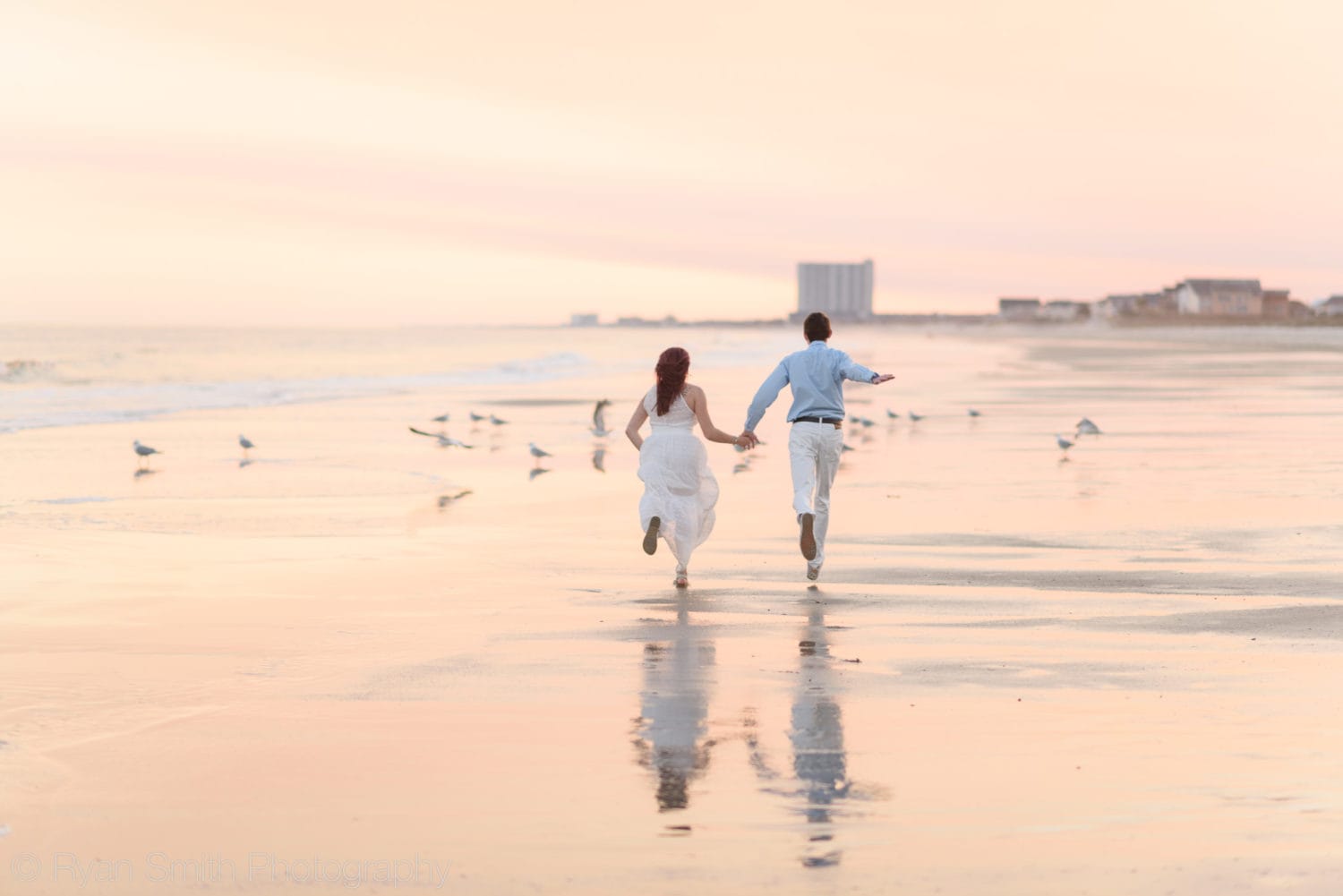 Couple holding hands running towards the seagulls  - Myrtle Beach State Park