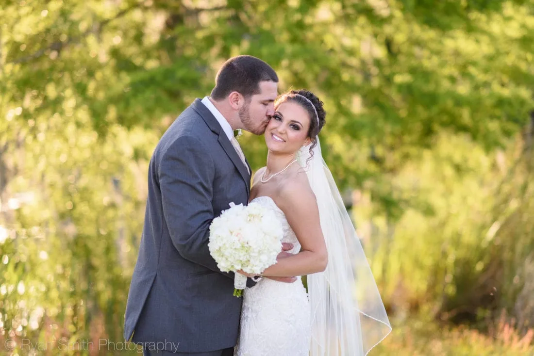 Groom kissing bride on the cheek - Upper Mill Plantation