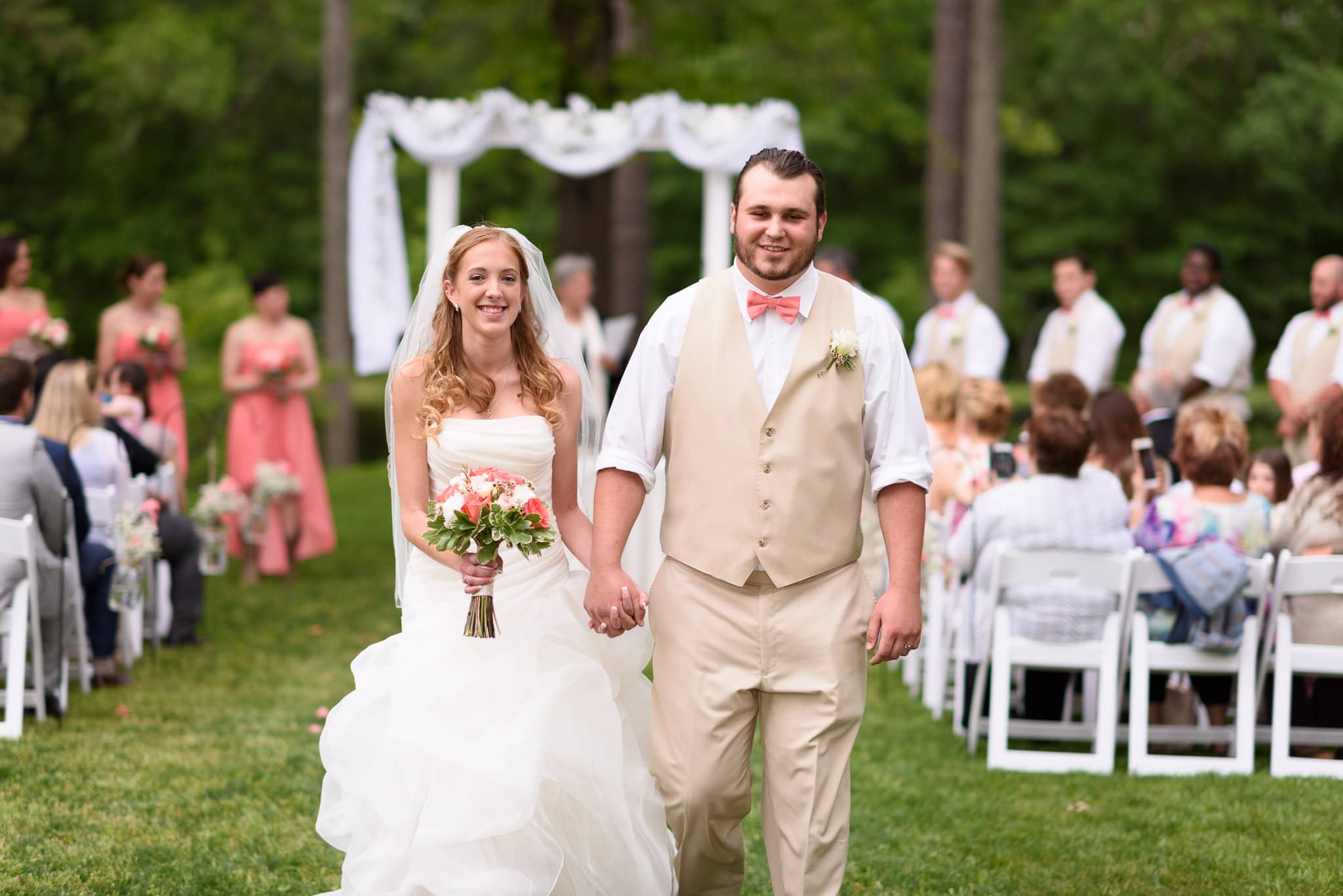 Happy couple walking away from ceremony holding hands - Wildberry Farm