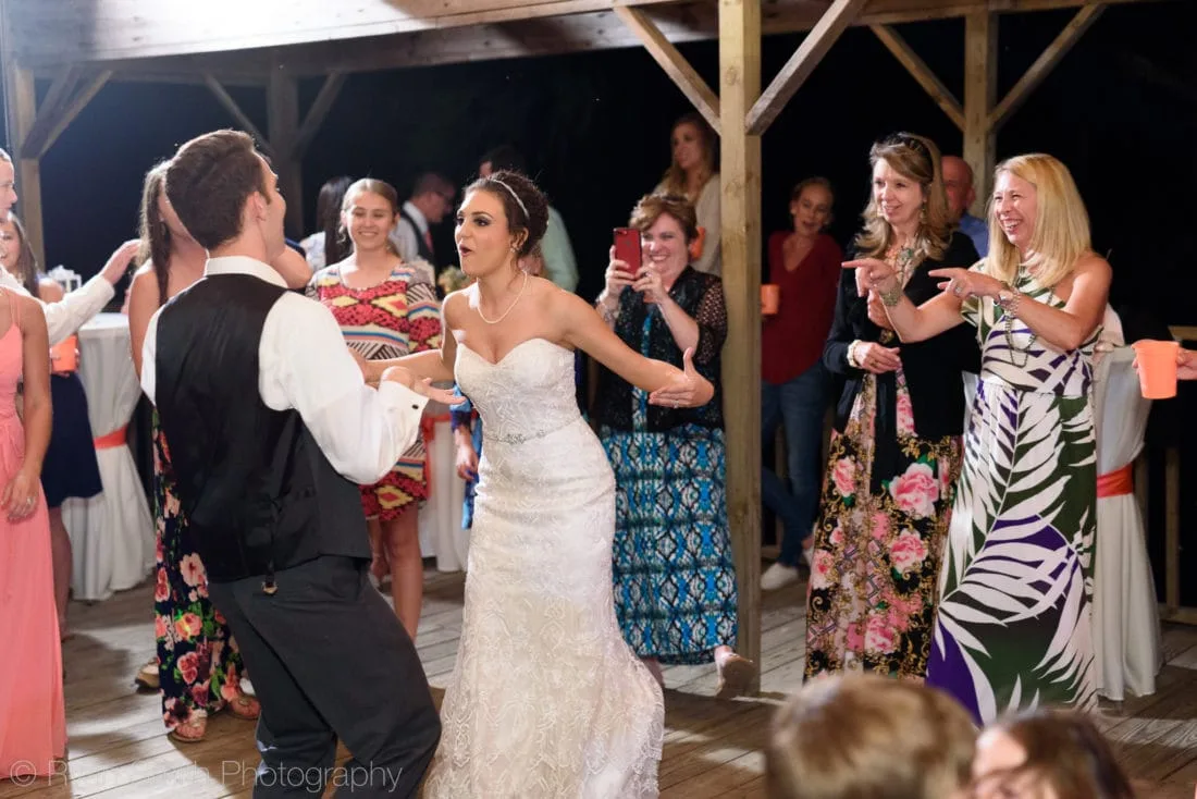 Bride dances with a groomsman as guests cheer on the dock at Upper Mill Plantation